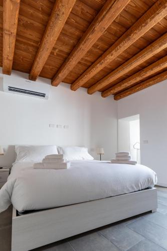 a white bedroom with a large bed with wooden ceilings at Piazza del Lago Suites - Menaggio in Menaggio