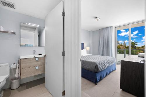 a bedroom with a bed and a bathroom with a window at ABAE Hotel by Eskape Collection in Miami Beach