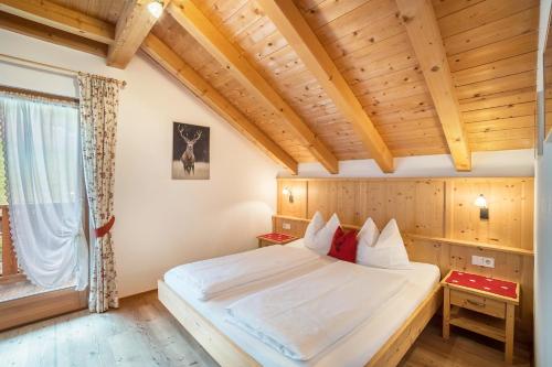 - une chambre avec un grand lit dans une pièce dotée de plafonds en bois dans l'établissement Stoffnerhof Apt Alpenrose, à Monguelfo-Tesido