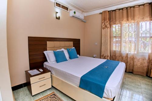 a bedroom with a large bed with blue pillows at Benru Suites Hotel in Kampala