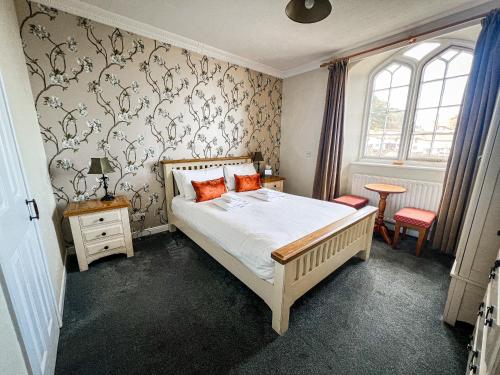 Schlafzimmer mit einem Bett mit weißer Bettwäsche und orangefarbenen Kissen in der Unterkunft Rock House Hotel in Lynmouth