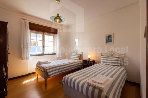 two beds in a room with a window at Casa do Pedro by ACasaDasCasas in Ericeira