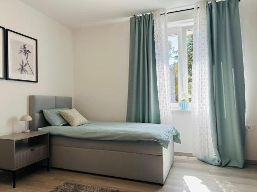 een slaapkamer met een bed met blauwe gordijnen en een raam bij Luxury apartment magical Portorose in Portorož
