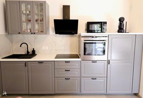 een keuken met witte kasten, een wastafel en een magnetron bij Luxury apartment magical Portorose in Portorož