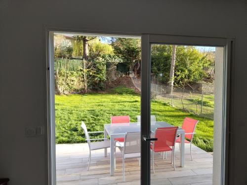 une porte en verre menant à une terrasse avec une table et des chaises. dans l'établissement Le Soleil au Paradis (des Pyrénées), à Vernet-les-Bains