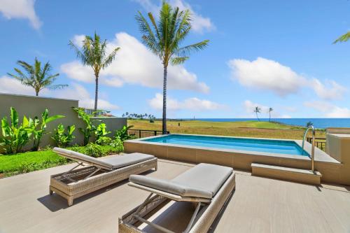 a swimming pool with two lounge chairs and the ocean at Timbers 3003 condo in Lihue