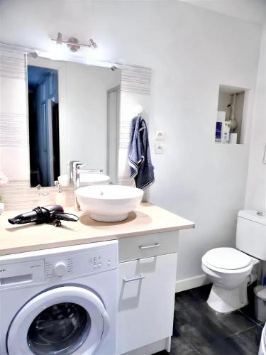 une salle de bain blanche avec une machine à laver et un lavabo dans l'établissement Appartement confortable au cœur de Nice - Vue sur la ville, à Nice
