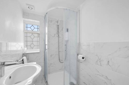 a white bathroom with a shower and a sink at Pass the Keys Beautiful spacious 7 bed in Hornchurch