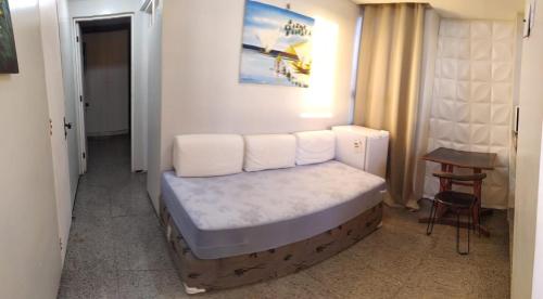 a bed in a room with a table and a stool at Tabajara Flat 807 Com piscina in Fortaleza