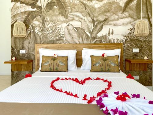 a bed with a heart made out of flowers at Lions SUITE&APARTMENT Ocean Front Beach & Pool in Bunju