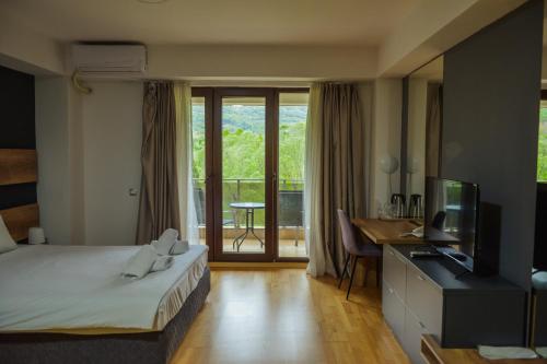 a hotel room with a bed and a television and a balcony at Park Golden View Hotel Casino in Ohrid