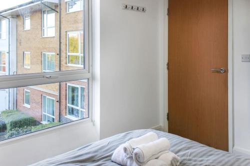 ein Schlafzimmer mit einem Fenster und Handtüchern auf einem Bett in der Unterkunft Modern 2-Bed in Watford Centre in Watford