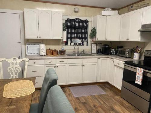 a kitchen with white cabinets and a table in it at Texas Tranquility Your Ideal Orange Rental Homes in Orange