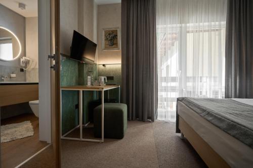 a hotel room with a bed and a desk with a television at Hotel Vedmezhyi Dvir in Bukovel
