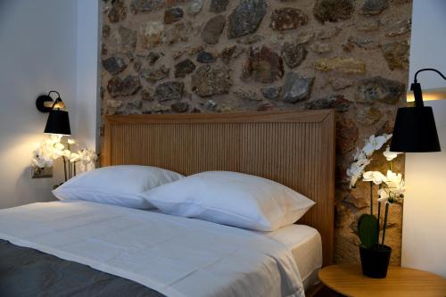 a bed with white pillows and a stone wall at Authentic Plaka Home in Athens