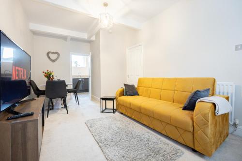 a living room with a yellow couch and a tv at Church Street Cottage Great Harwood in Great Harwood