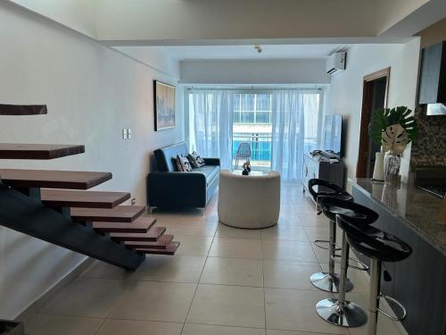 ein Wohnzimmer mit einer Treppe und ein Wohnzimmer mit einem Sofa in der Unterkunft Ejecutivo penthouse en santo domingo in Santo Domingo