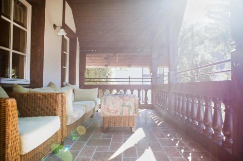 a porch with wicker chairs and a couch on a balcony at Villa Titina in Miedzygorze