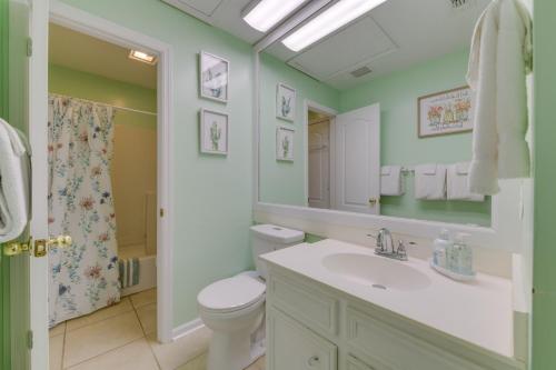a bathroom with a sink and a toilet and a mirror at Cozy PCB Condo Less Than half Mile to Public Beach Access! in Panama City Beach