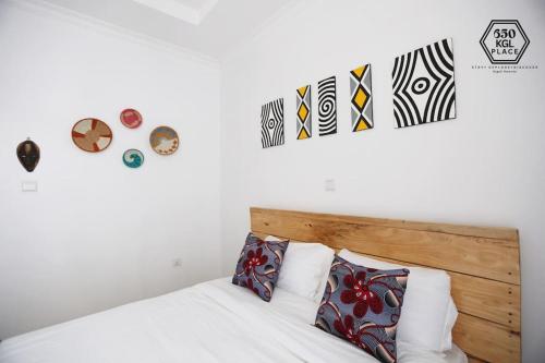 吉佳利的住宿－Cozy Oasis Large Apt in Center of Kigali Rwanda，一间卧室配有一张带木制床头板的床,墙上挂有艺术品。