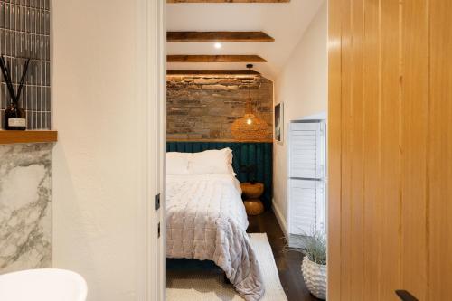 a bedroom with a bed and a brick wall at Hive Townhouse in Aberaeron