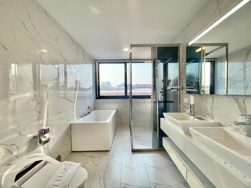 a white bathroom with two sinks and a tub at Pupae Pool Villa Pattaya in Pattaya South