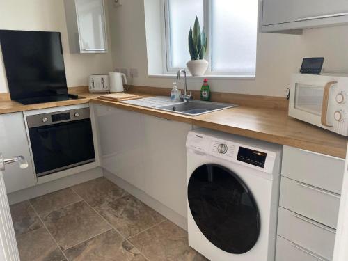 uma cozinha com uma máquina de lavar roupa e um lavatório em The Cwtch Pet Friendly Ground Floor Flat Near M4 and Porthcawl em Kenfig Hill