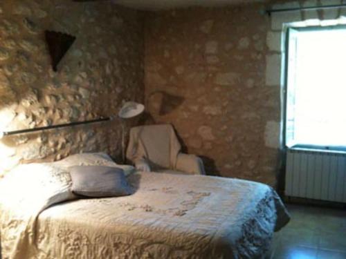 une chambre avec un lit et un mur en pierre dans l'établissement Bastide en pierre dans le Luberon, à Cheval-Blanc