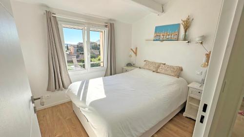 une chambre blanche avec un lit et une fenêtre dans l'établissement Les Bastides de Guerrevieille, à Sainte-Maxime