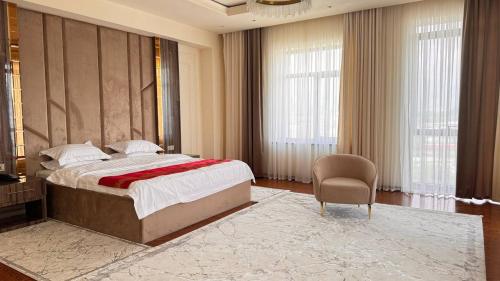 a bedroom with a large bed and a chair at Kangurt Grand Hotel in Dushanbe