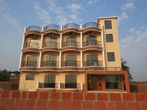 a tall building with balconies on top of a brick wall at SV Inns Sea Pearl in Devgarh