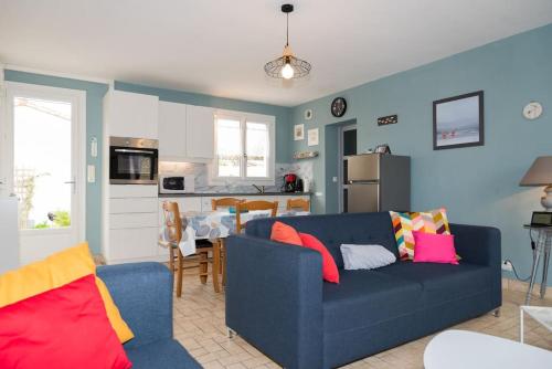 ein Wohnzimmer mit einer blauen Couch und einer Küche in der Unterkunft Jolie maison au calme - 300m de la plage - Terrasse - Barbecue in Saint-Michel-Chef-Chef