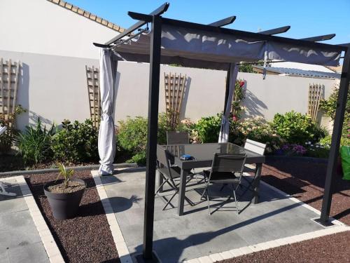 einen Tisch und Stühle unter einem Baldachin auf einer Terrasse in der Unterkunft Jolie maison au calme - 300m de la plage - Terrasse - Barbecue in Saint-Michel-Chef-Chef