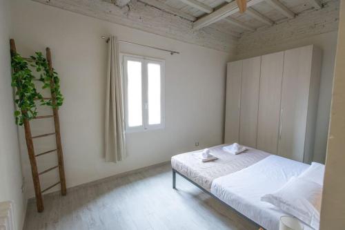 a white bedroom with a bed and a window at Stazione - Arno River apartment in Florence