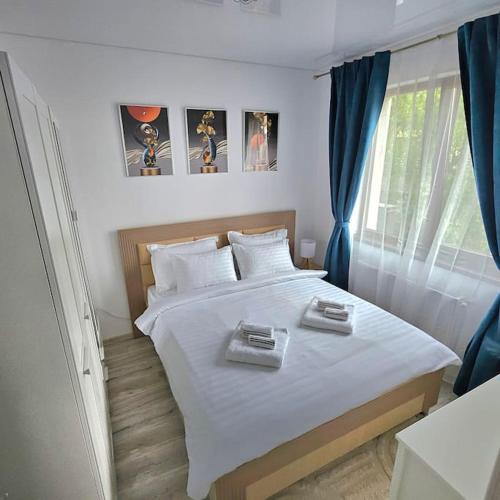 Un dormitorio con una cama blanca con dos platos. en Cozy SoRaDa 2 apartment, en Bragadiru