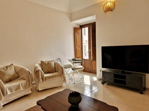 un soggiorno con 2 sedie e una TV a schermo piatto di Casa Matteo-Gran Sasso a L'Aquila