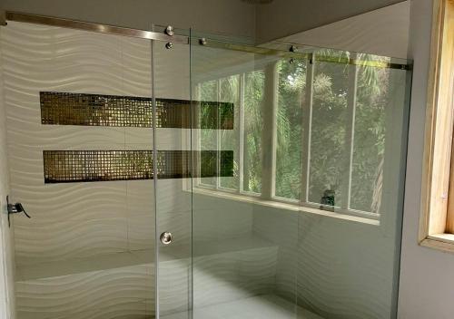 La salle de bains est pourvue d'une douche en verre et d'une fenêtre. dans l'établissement HOTEL SANTAFE NATURA - SANTAFE DE ANTIQUIA, à Santa Fe de Antioquia