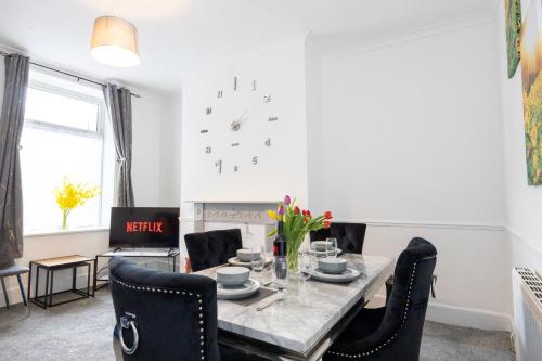 a dining room table with chairs and a clock on the wall at Cosy Three Bedroom Terrace Rishton in Rishton