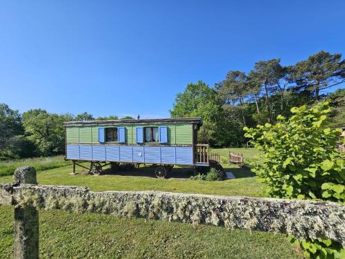a house sitting in a field next to a stone fence at Roulotte Fleur des Champs in Sigalens