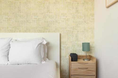 a bedroom with a bed and a nightstand with a lamp at Belem Design Apartments by Homing in Lisbon