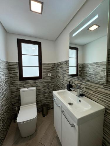 a bathroom with a toilet and a sink and a mirror at Sea View Apartment in Manilva
