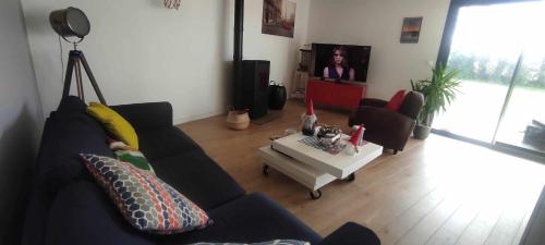 un salon avec un canapé et une télévision dans l'établissement Maison à louer 80 em anniversaire du débarquement, à Sainte-Marie-du-Mont