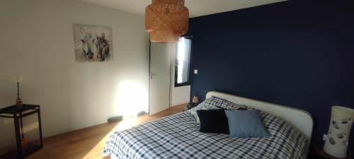 une chambre avec un lit avec un mur bleu dans l'établissement Maison à louer 80 em anniversaire du débarquement, à Sainte-Marie-du-Mont