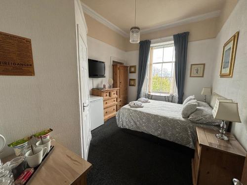 Clarin Guest House في إدنبرة: غرفة نوم فيها سرير وتلفزيون