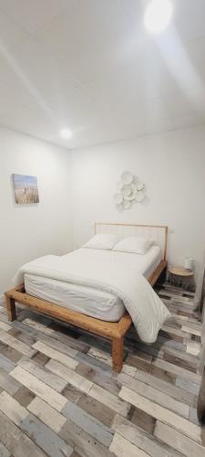 une chambre blanche avec un lit en bois sur un plancher en bois dans l'établissement Le Rayon de Soleil, à Mimizan
