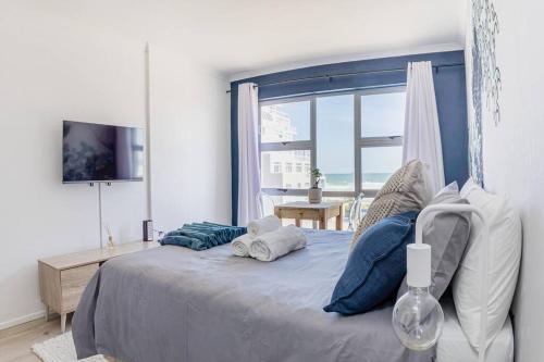 ケープタウンにあるBeach & Sea View Facing Apartment Japanese Styledの大きなベッドと大きな窓のある寝室