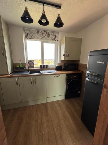 a kitchen with white cabinets and a black refrigerator at Modern Luxury apartment Liverpool in Liverpool