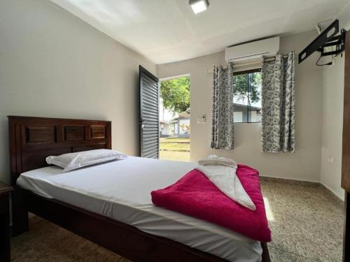 um quarto com uma cama com um cobertor vermelho em Pousada Cidade Linda em Foz do Iguaçu