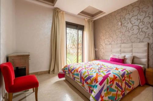1 dormitorio con 1 cama y 1 silla roja en Maison 3 chambres en Marrakech