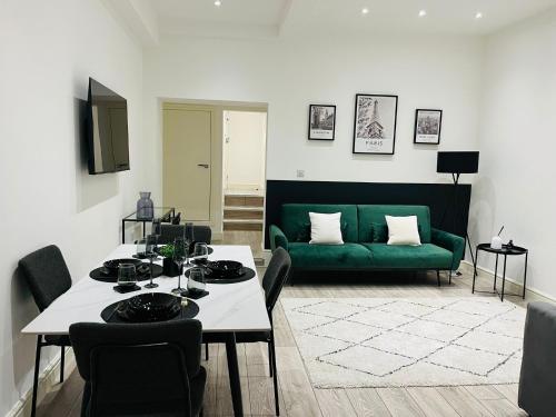 a living room with a green couch and a table at High-Spec Apartment in London - City Centre & Next To Tube in Ealing